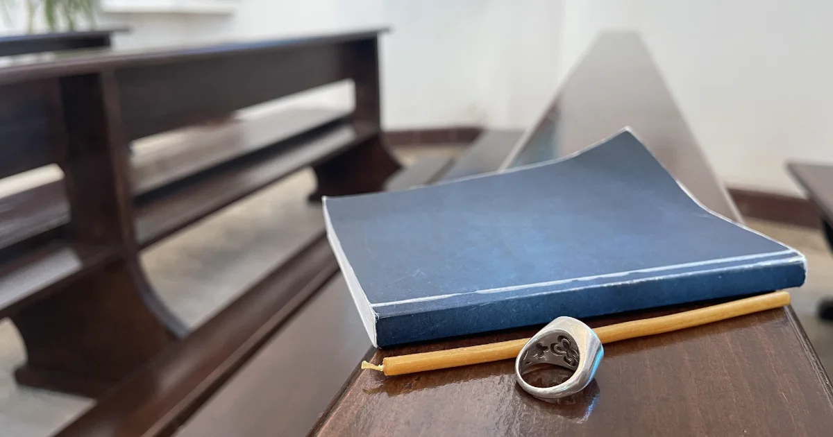 EIn Buch mit einem Stift und einem Ring auf einer Kirchenbank